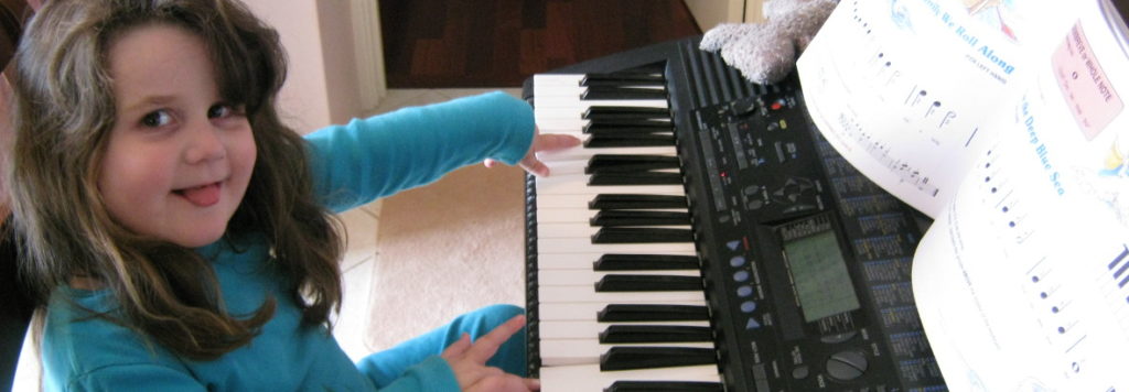A child pointing to a key on the keyboard during a music lesson